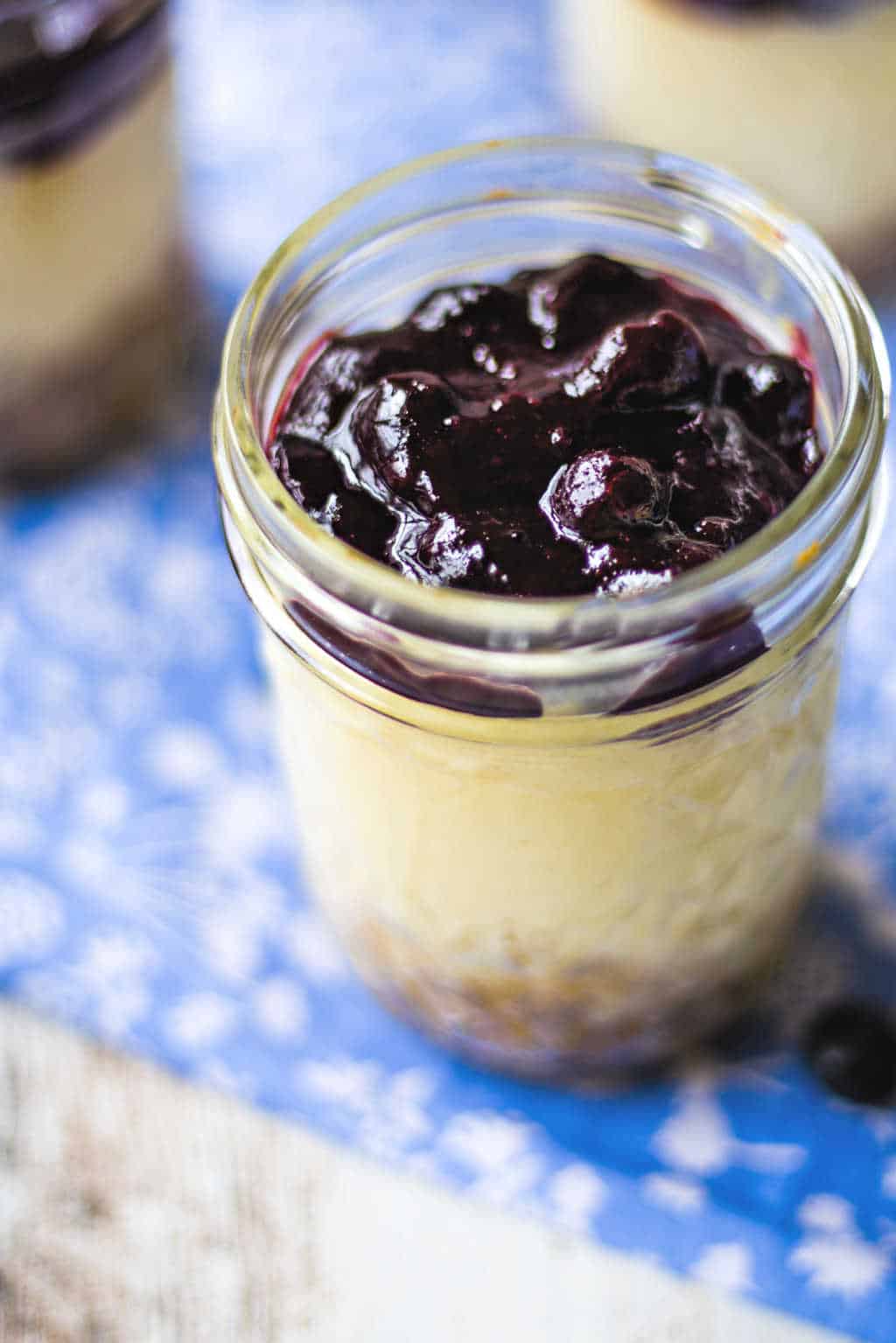 blueberry cheesecake in mason jars on a blue tablecloth
