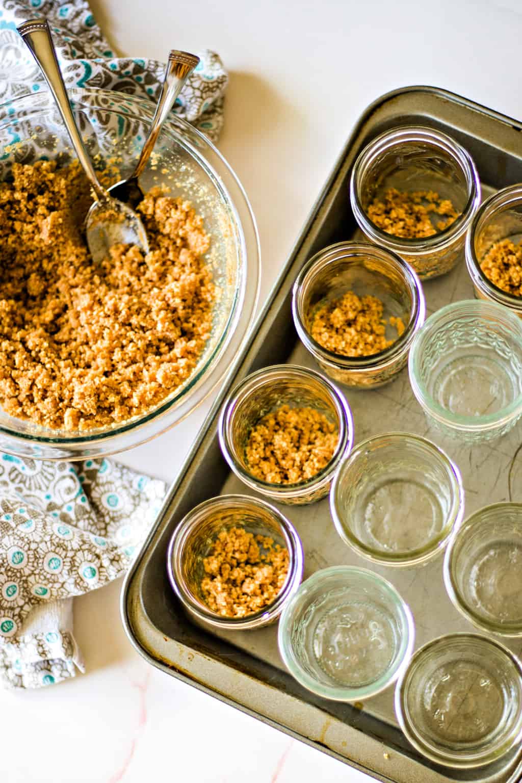 spooning graham cracker crust mixture into mason jars