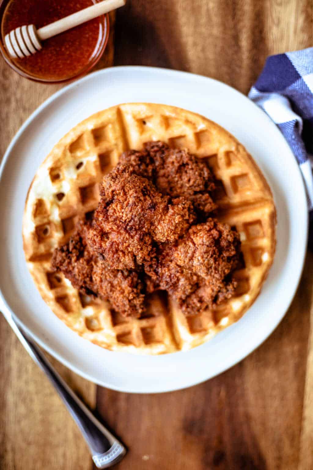 poulet et gaufres sur une assiette blanche avec une serviette à carreaux bleus