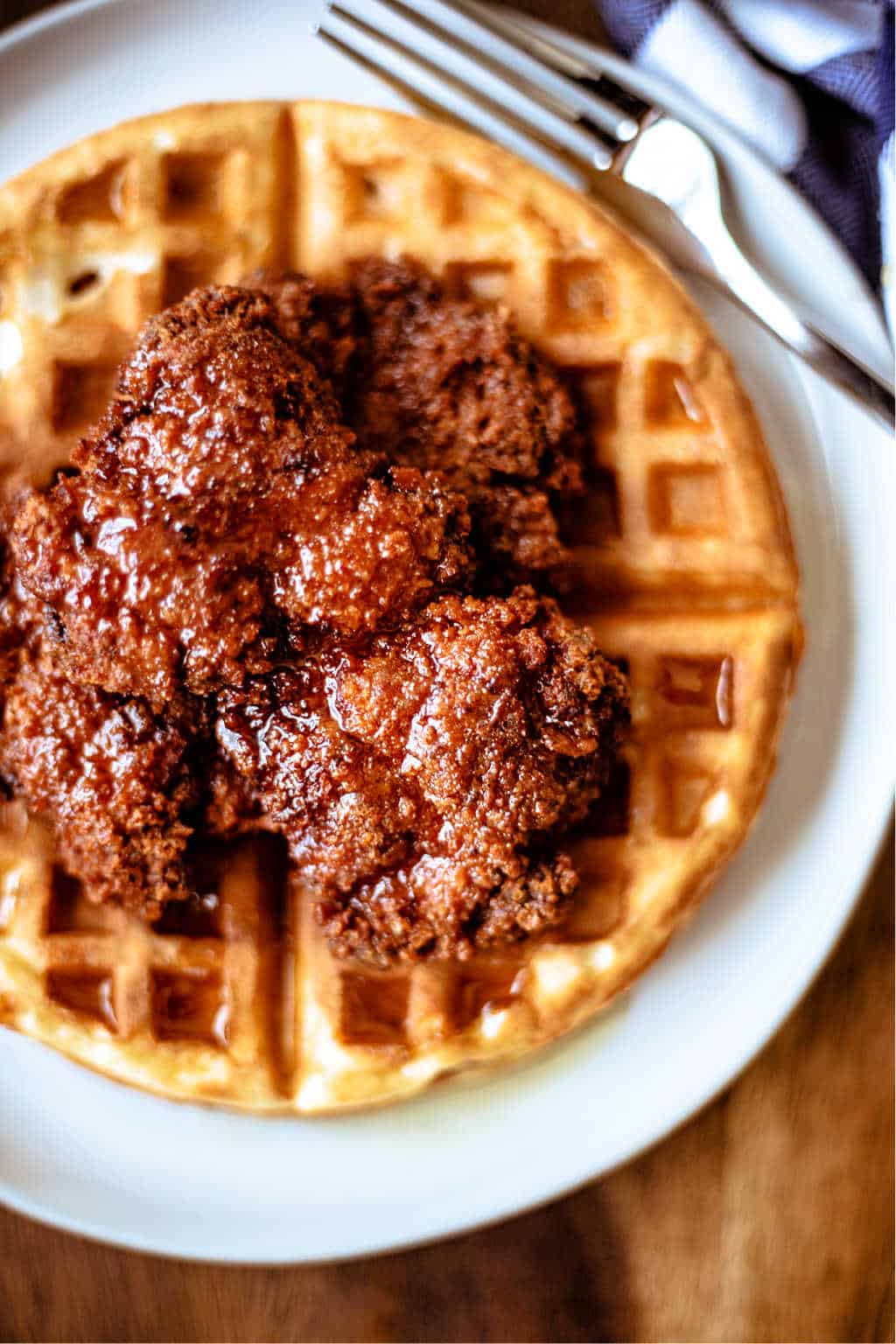 chicken and waffles with honey sriracha on a white plate with a fork