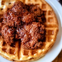 chicken and waffles with honey sriracha on a white plate