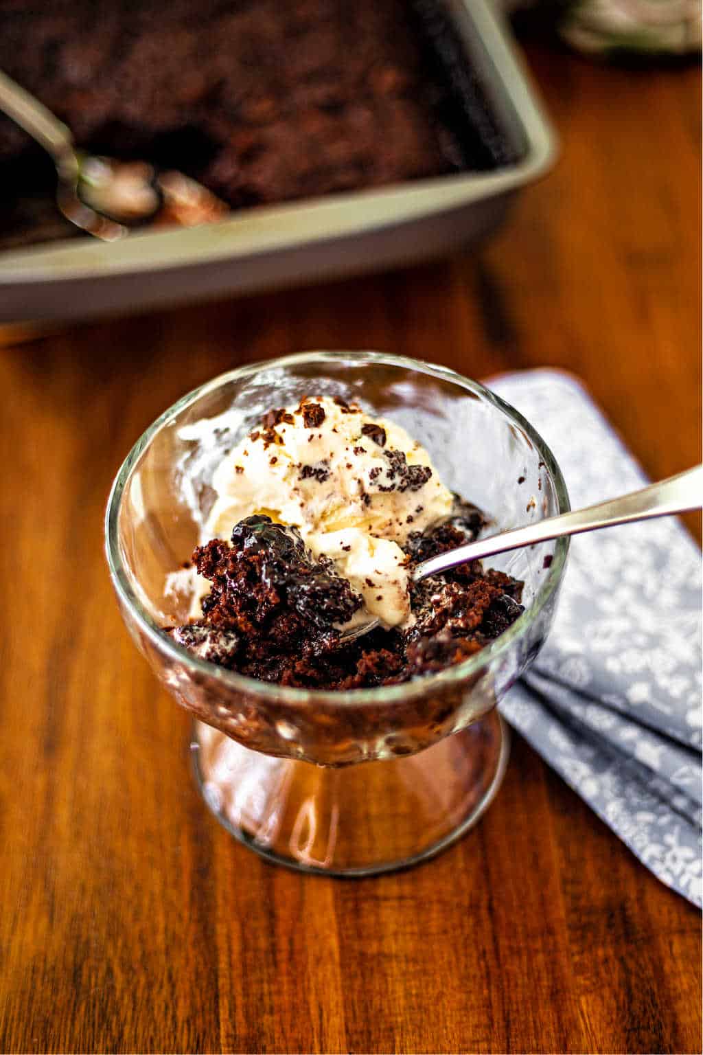 chocolate pudding cake in a glass dish with a scoop of vanilla ice cream