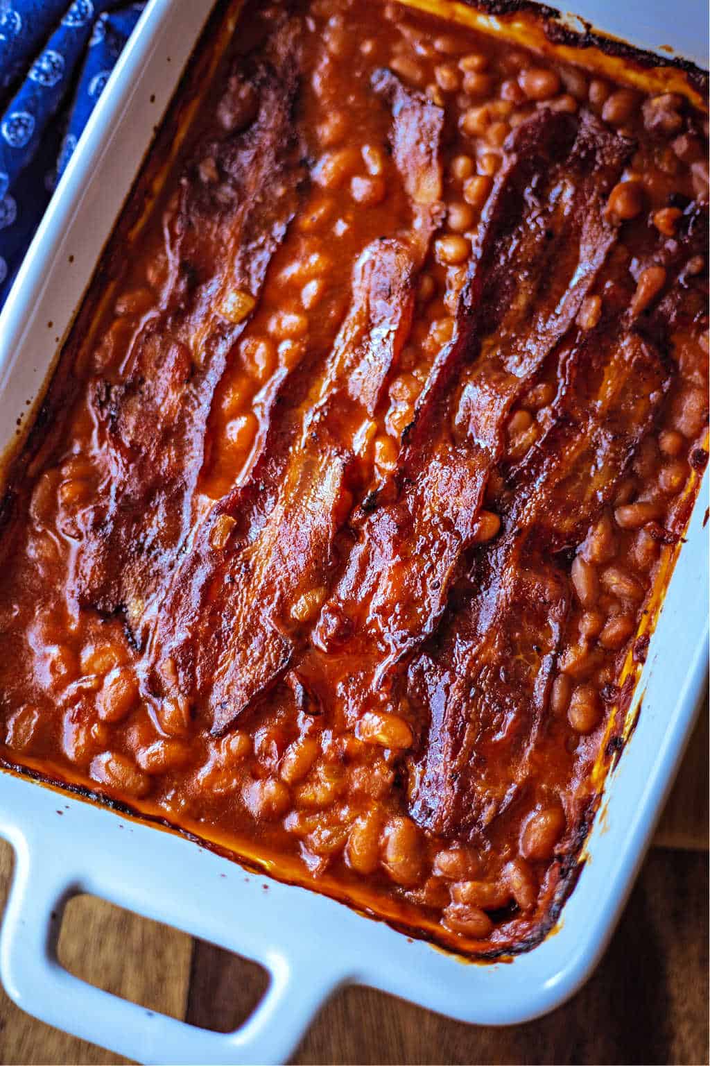 Easy Baked Beans with strips of bacon in a white baking dish