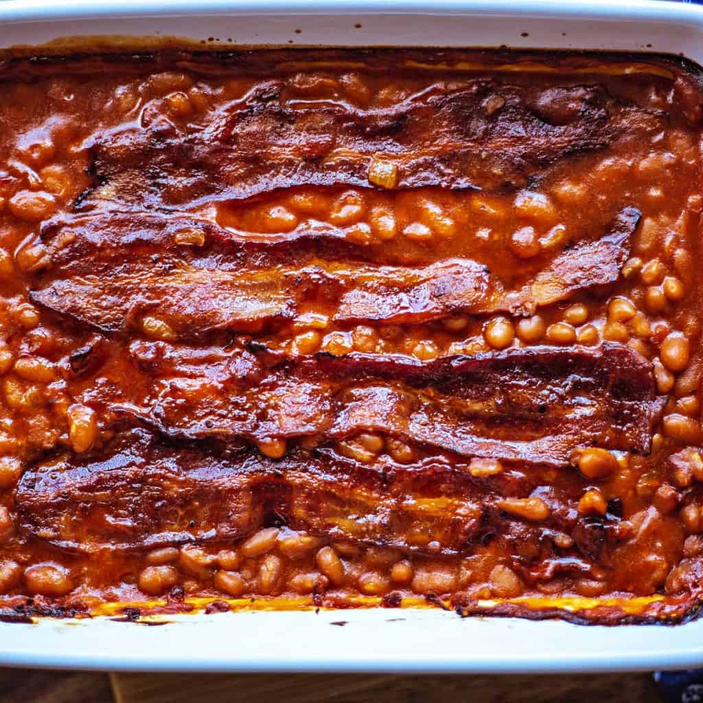 Easy Baked Beans with strips of bacon in a white baking dish