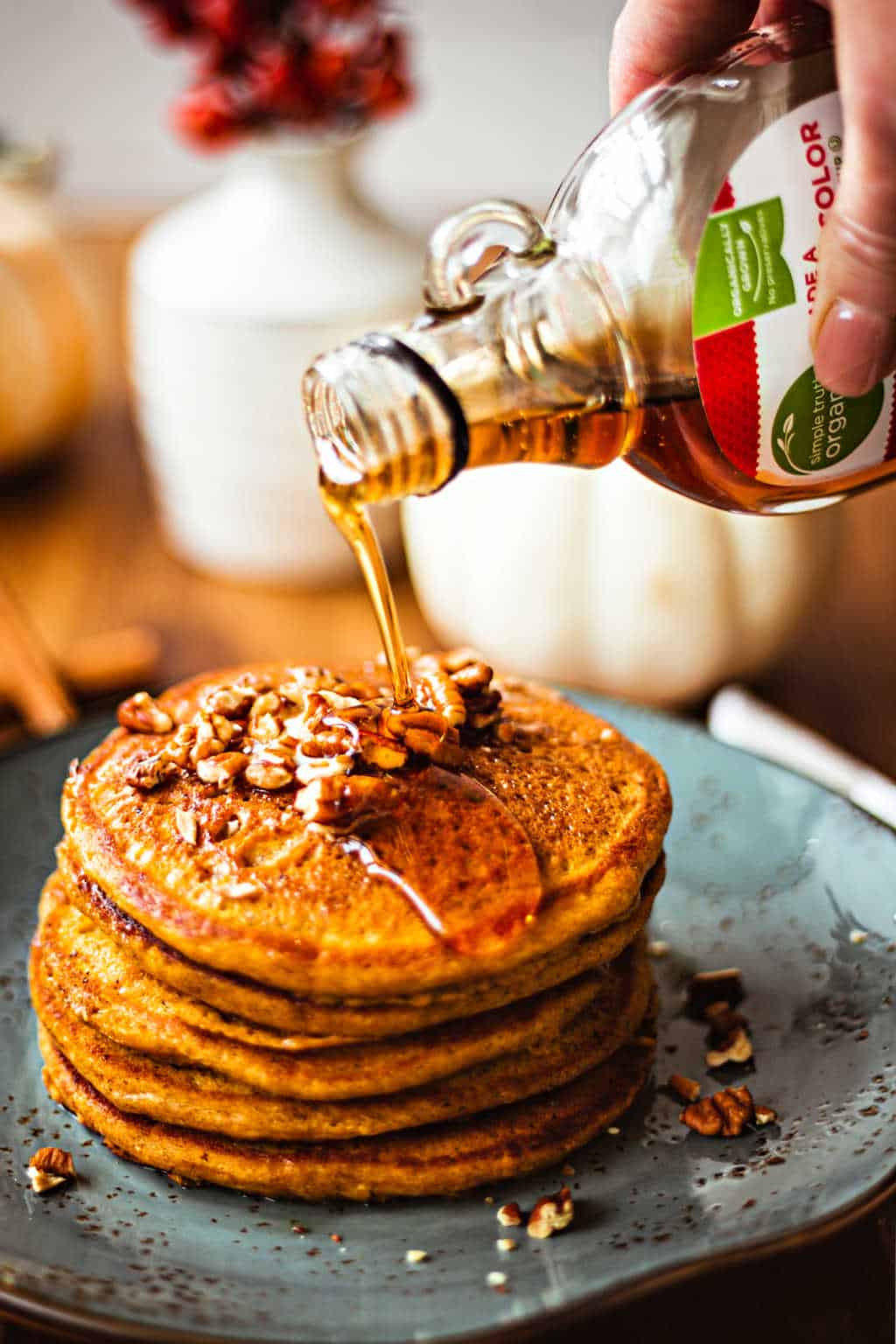 pouring maple syrup on pumpkin spice pancakes