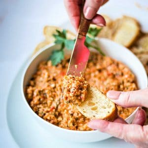 spreading roasted red pepper tapenade on a baguette