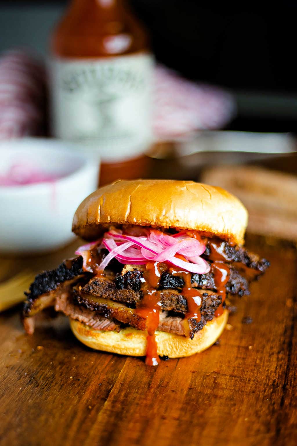 electric smoker brisket on a sandwich bun with pickled red onions and bbq sauce