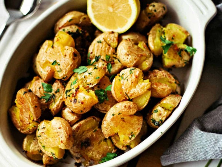 Lemon Garlic Smashed Potatoes with a lemon slice in a white dish