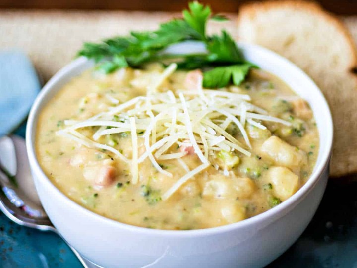 Italian Potato Broccoli Cheese Soup in a white bowl on a blue plate