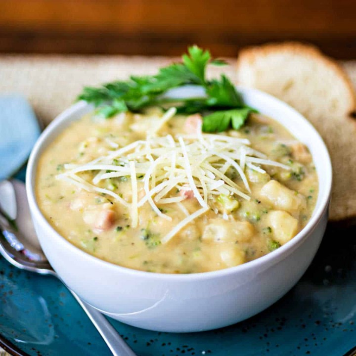 Italian Potato Broccoli Cheese Soup in a white bowl on a blue plate