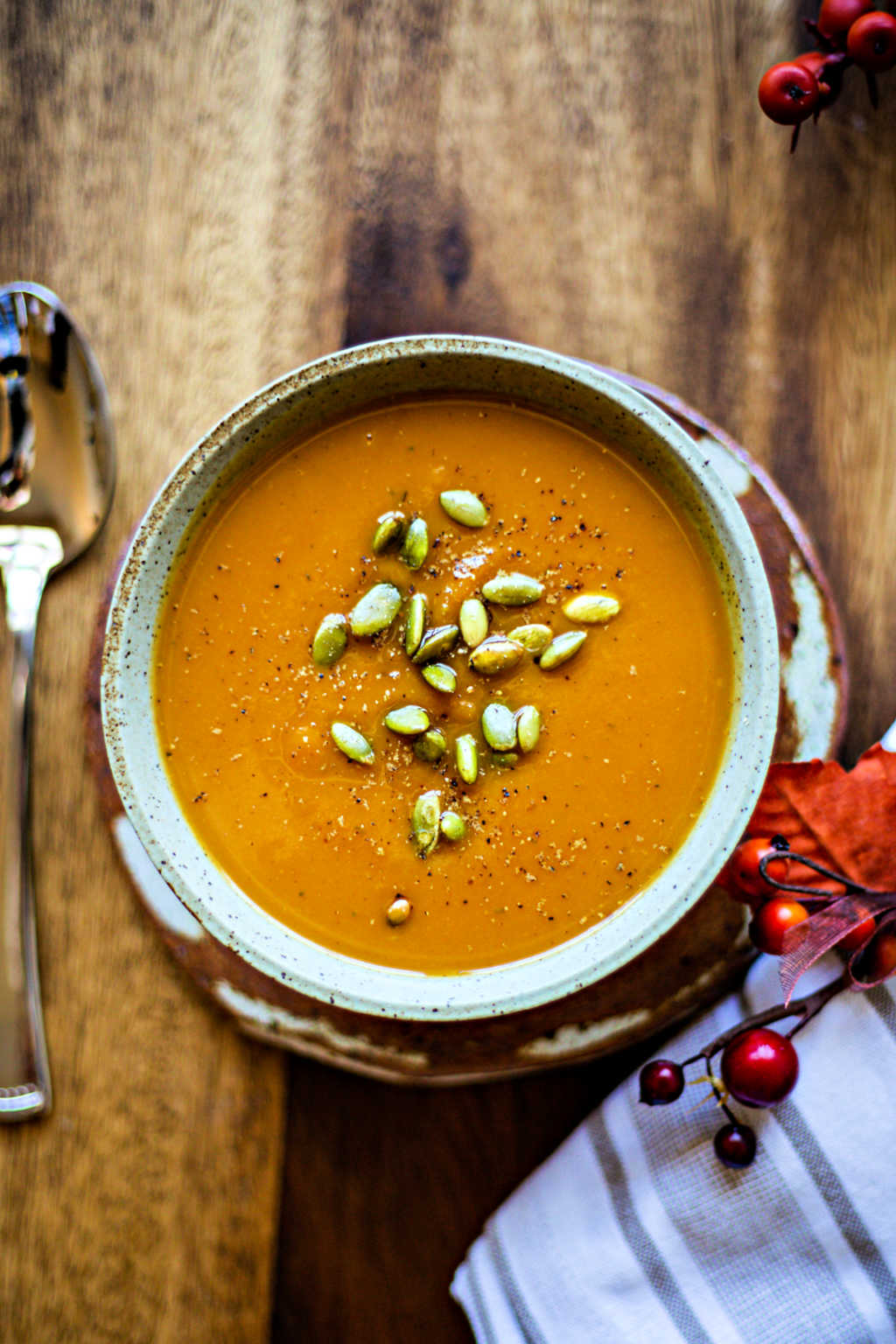a bowl of butternut squash soup on a wooden table