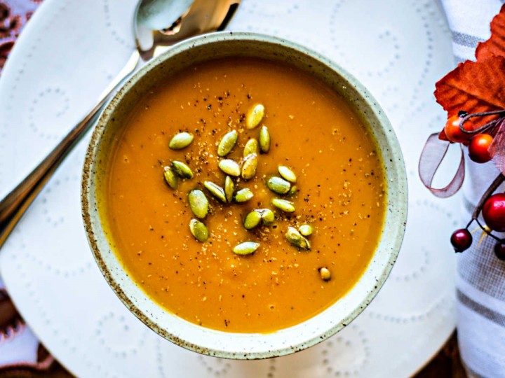 a bowl of butternut squash soup on a white plate