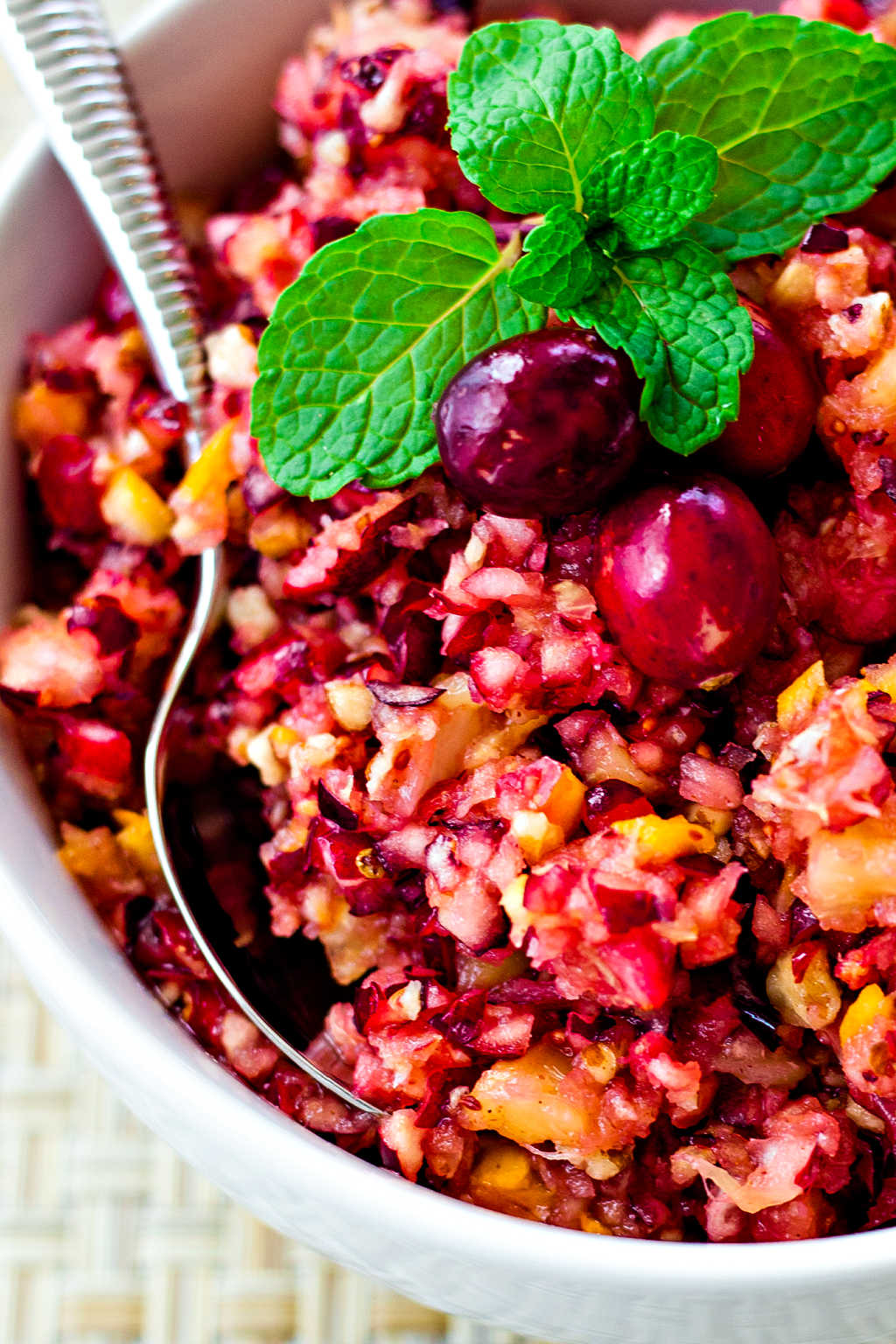 close up of cranberry relish in a white bowl garnished with fresh mint