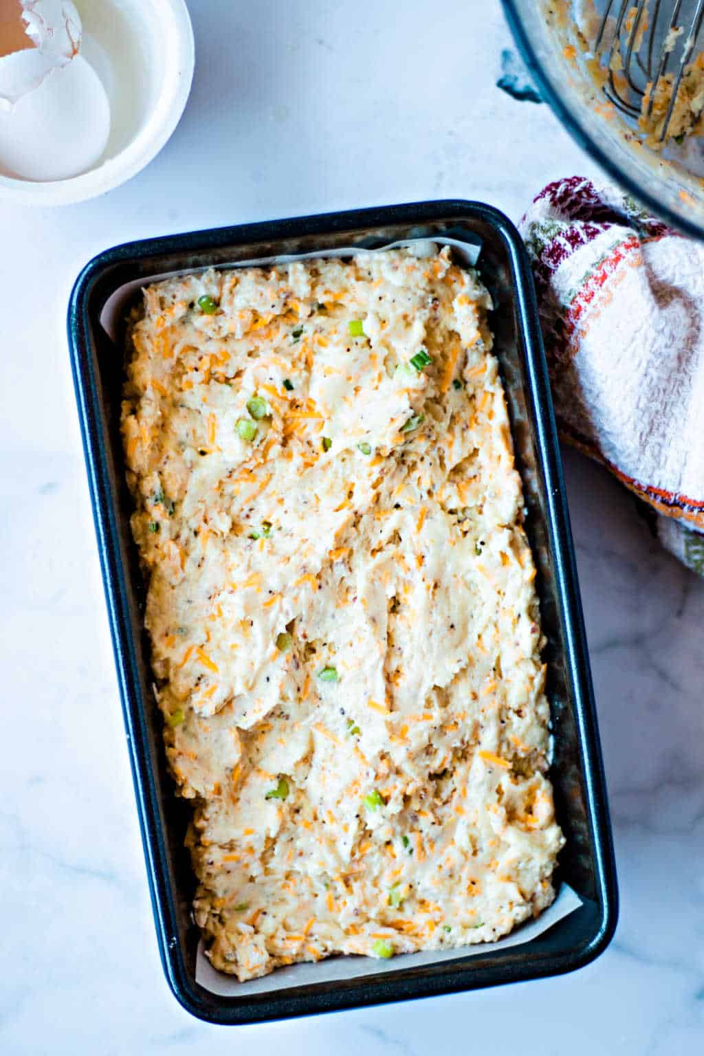 unbaked cheese bread batter in a loaf pan