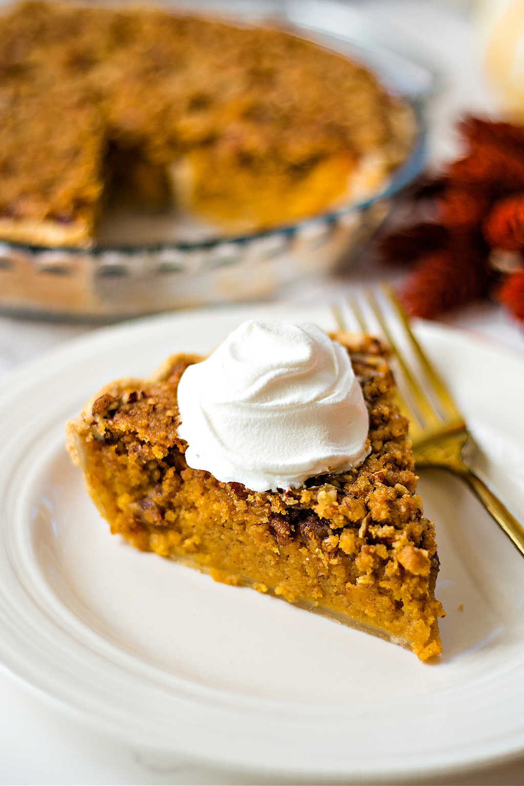 a slice of sweet potato pie with a dollop of whipped cream on a white plate