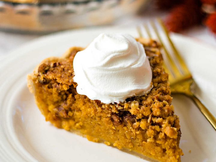 a slice of sweet potato pie with a dollop of whipped cream on a white plate