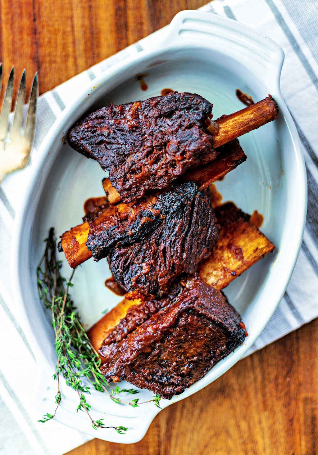 braised beef short ribs on a white platter on a wooden table