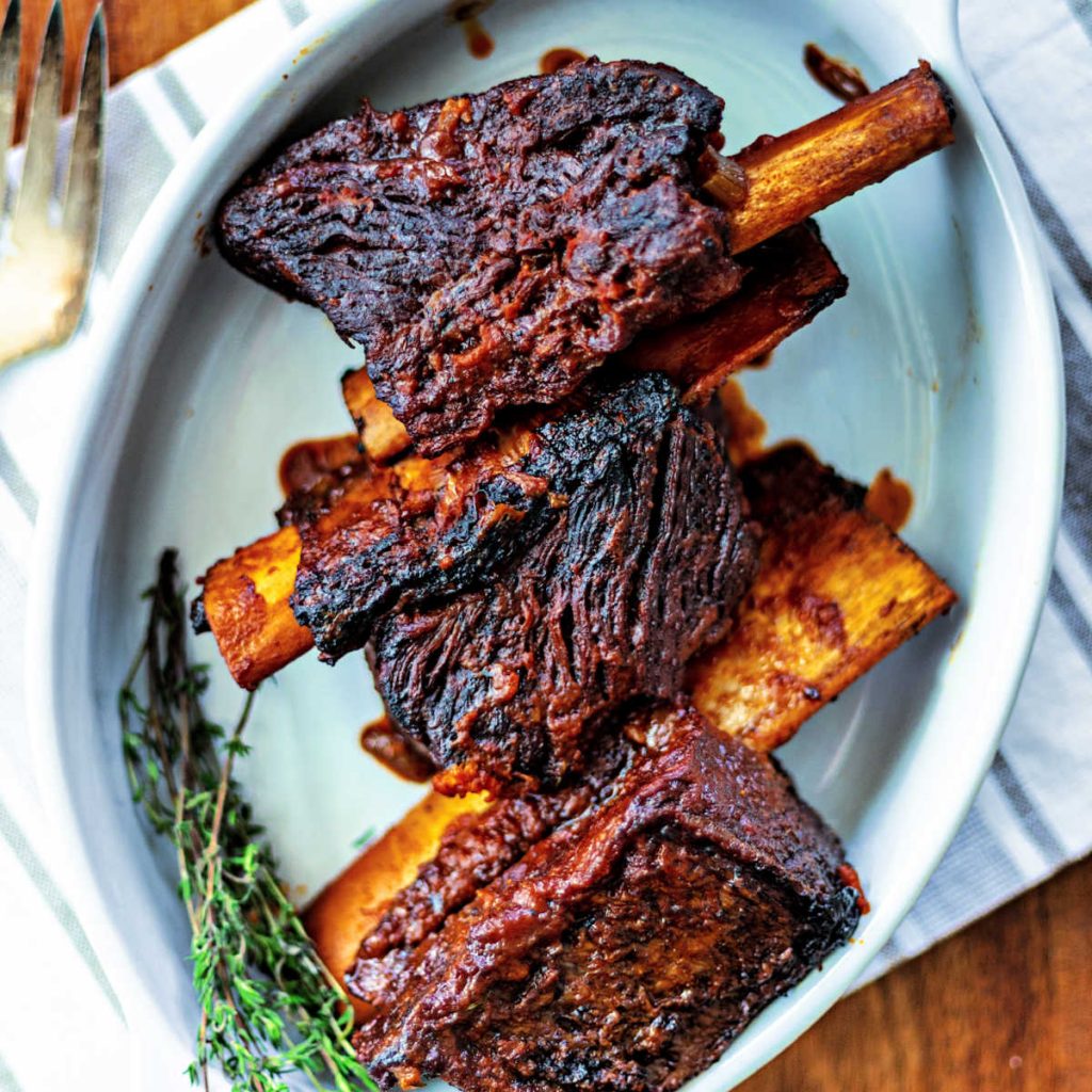 braised beef short ribs on a white platter on a wooden table
