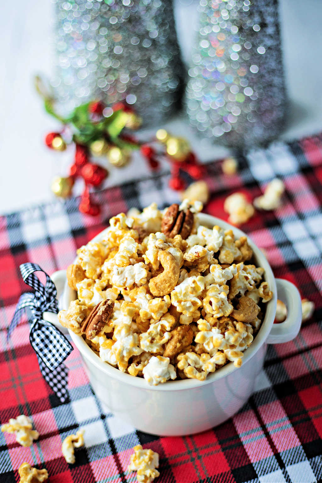 Nutty Caramel Corn in a white bowl on a Christmas plaid tablecloth