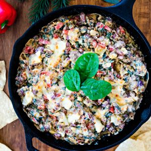 Sausage, Bean, and Spinach Dip in a cast iron skillet on a wooden table