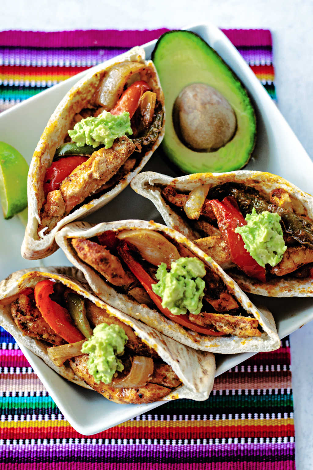 chicken fajita pitas on a white plate on top of a colorful placemat