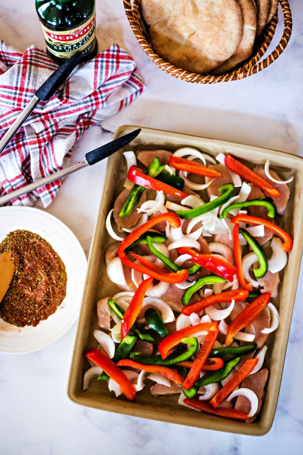 chicken, onion, and bell peppers on a baking sheet for chicken fajitas