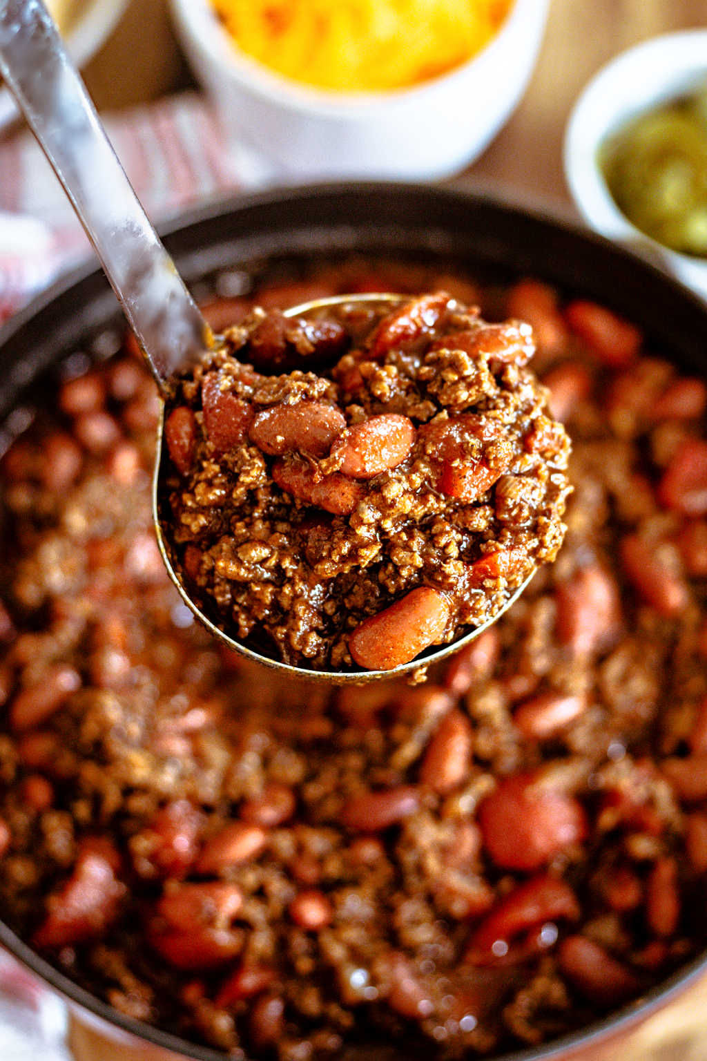 a ladle full of ground beef chili lifted out of a pot