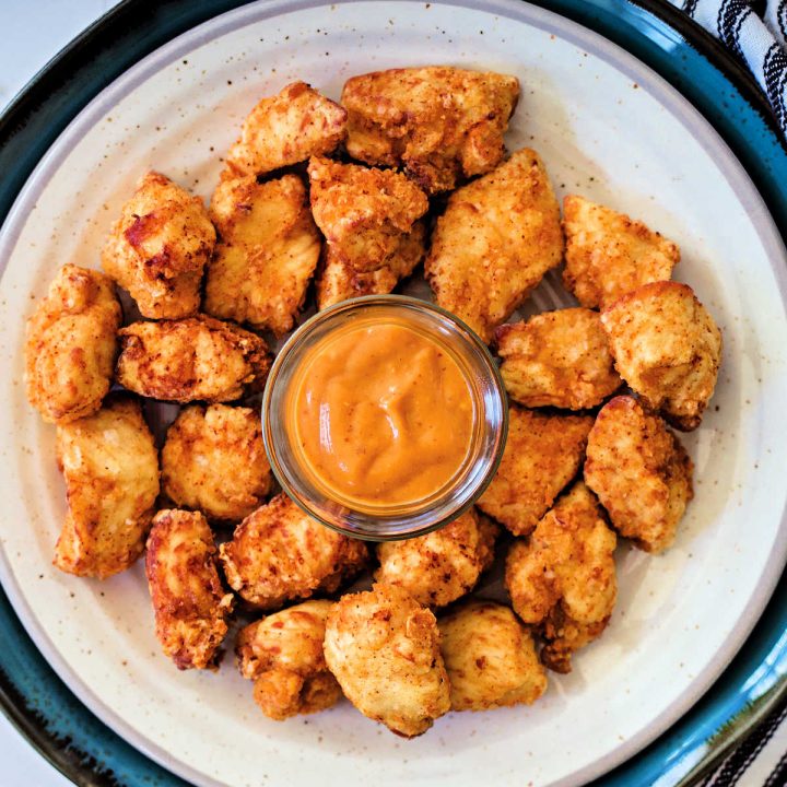 Chick-fil-A Chicken Nuggets on a white plate with a side of dipping sauce.