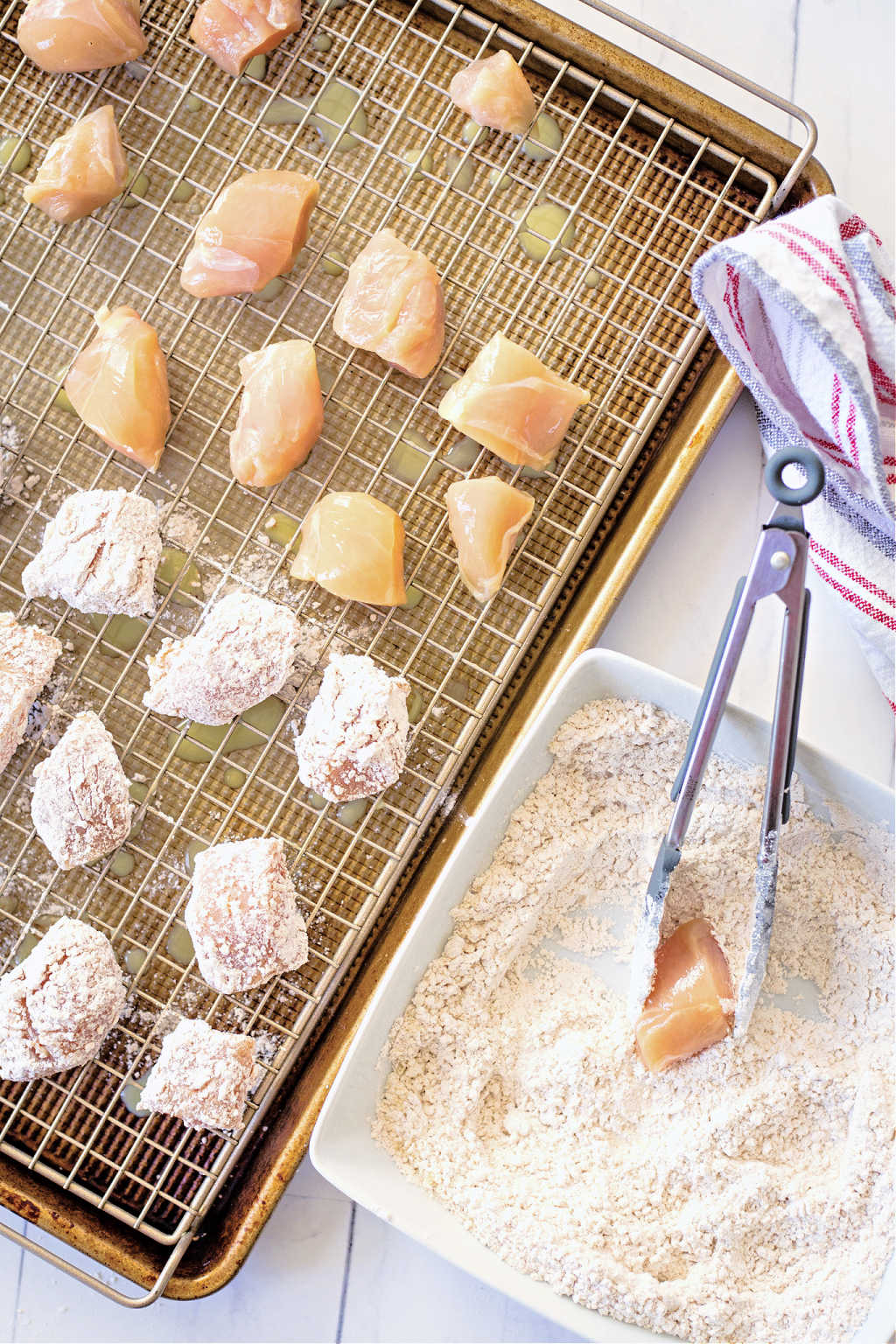 dredging chicken in a bowl of flour with tongs.