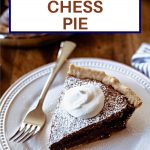 a slice of chocolate chess pie on a white plate on a wooden table.
