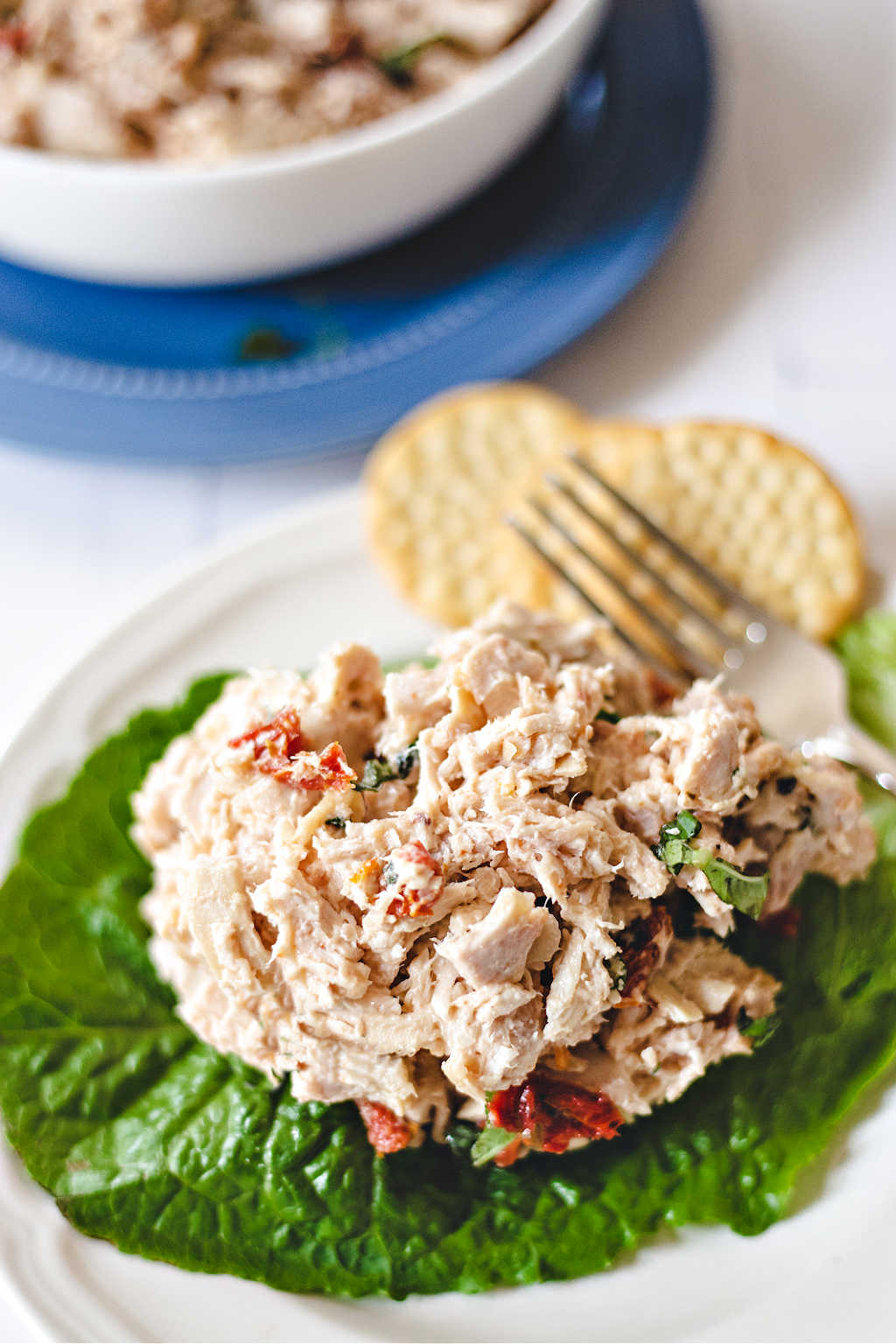 rotisserie chicken salad on a lettuce leaf on a white plate with crackers