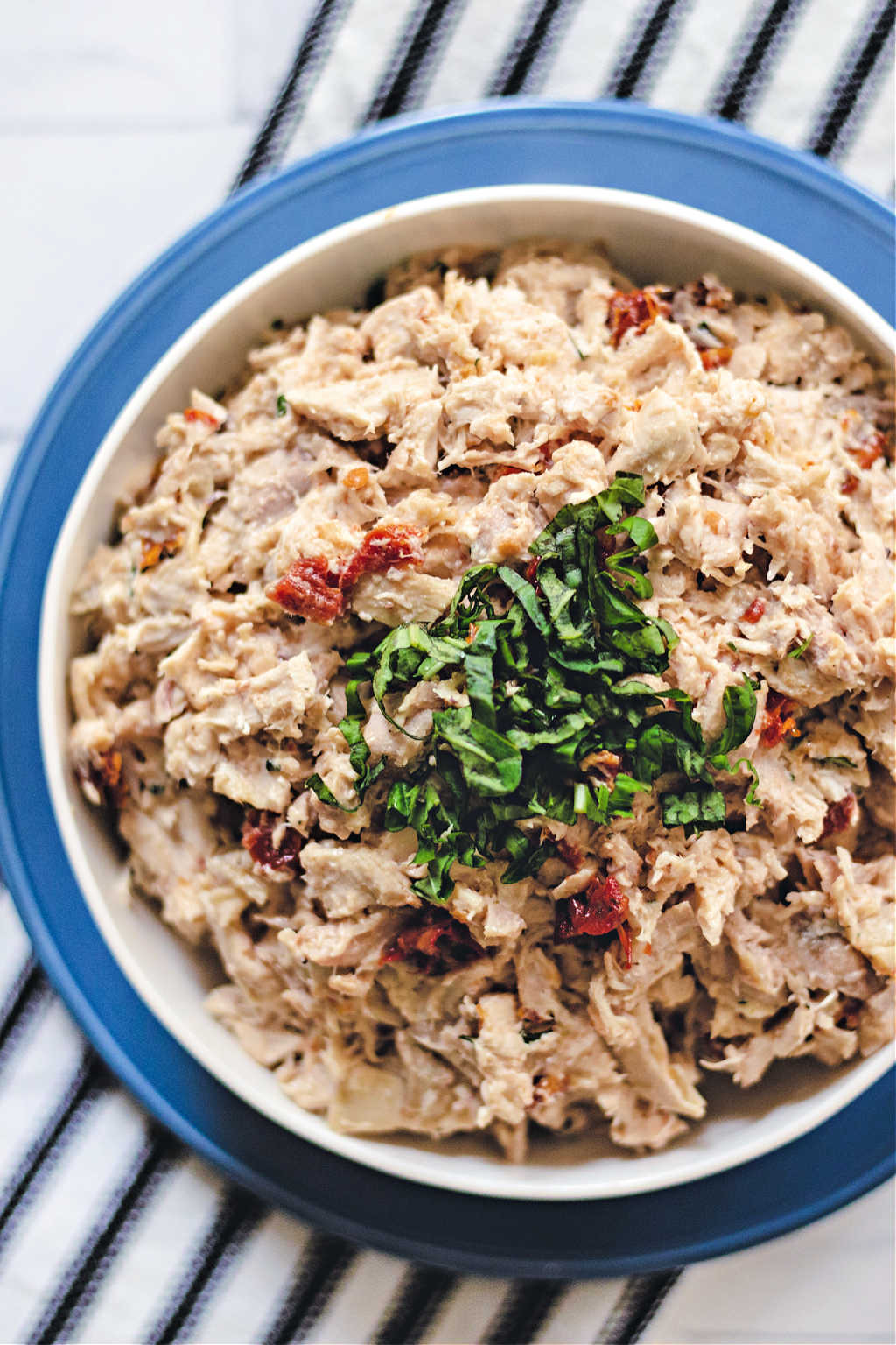 rotisserie chicken salad in a white bowl on a blue plate on a table