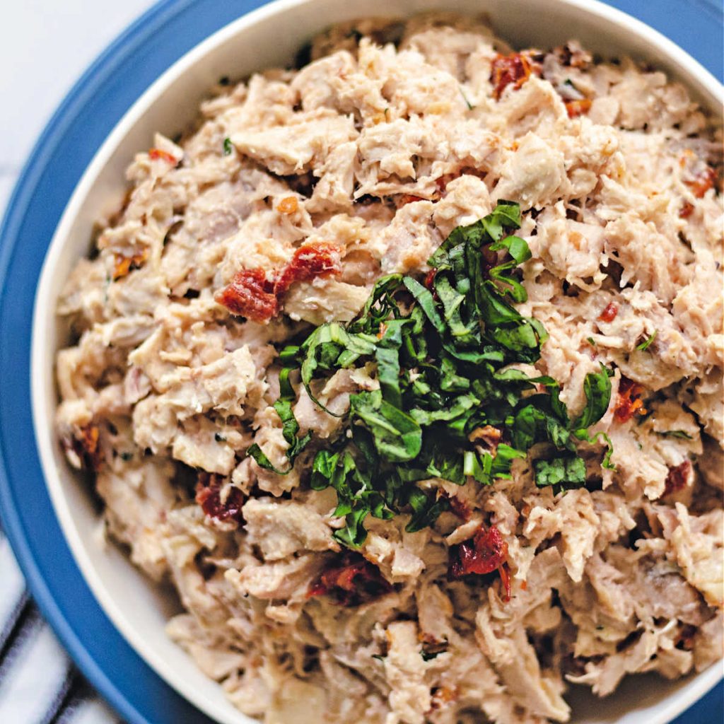 rotisserie chicken salad in a white bowl on a blue plate on a table