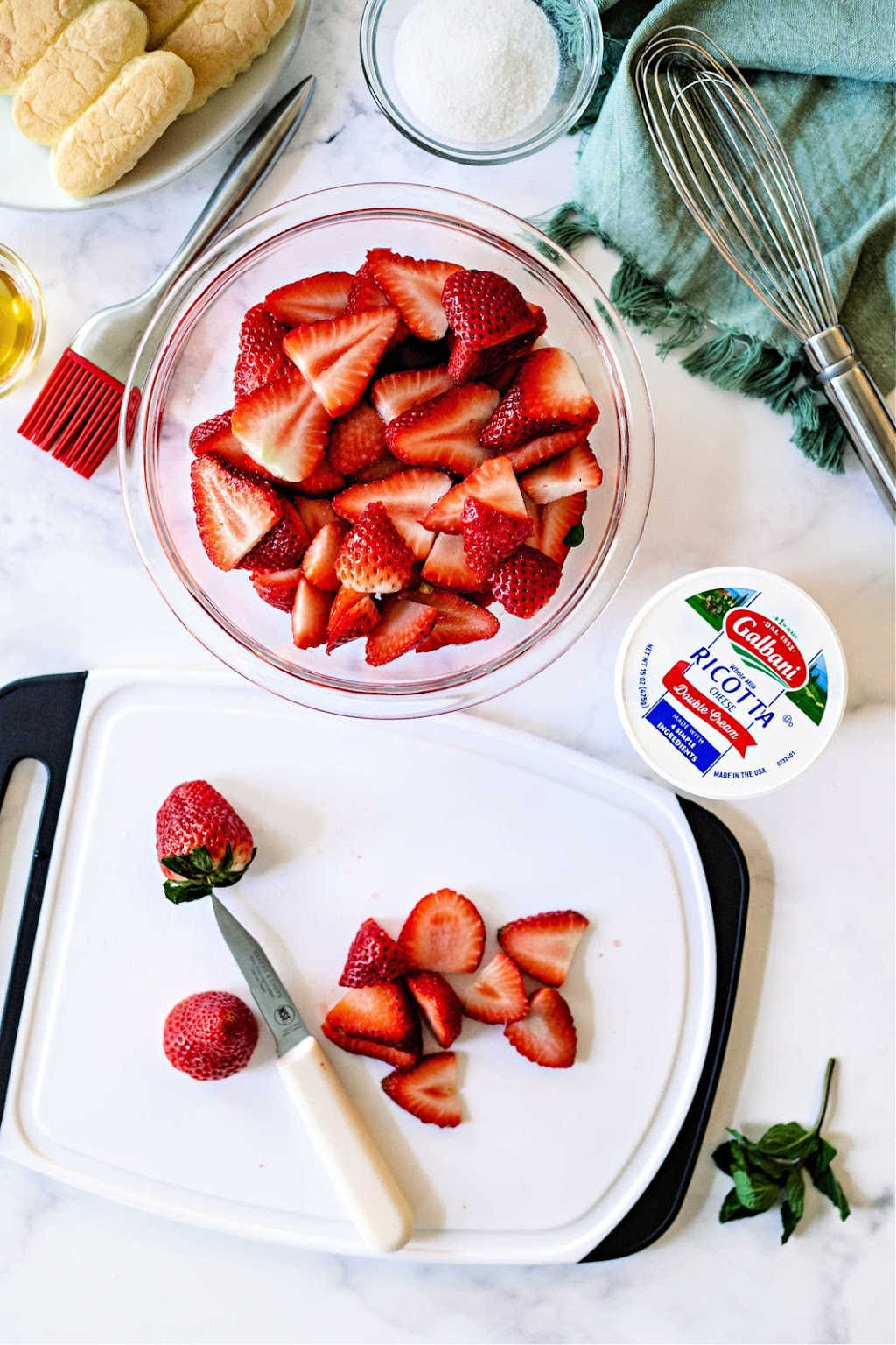 sliced strawberries in a glass bowl on a table.