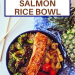 teriyaki salmon in a bowl with brown rice, roasted broccoli, red bell pepper, and pineapple on a wooden table
