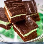 fudge mint brownies on a pedestal plate with a sprig of mint.