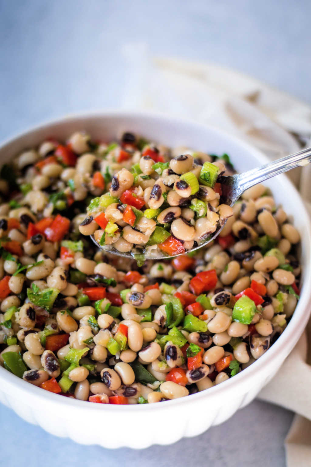 close up of a spoonful of black eyed pea salad in a white bowl.