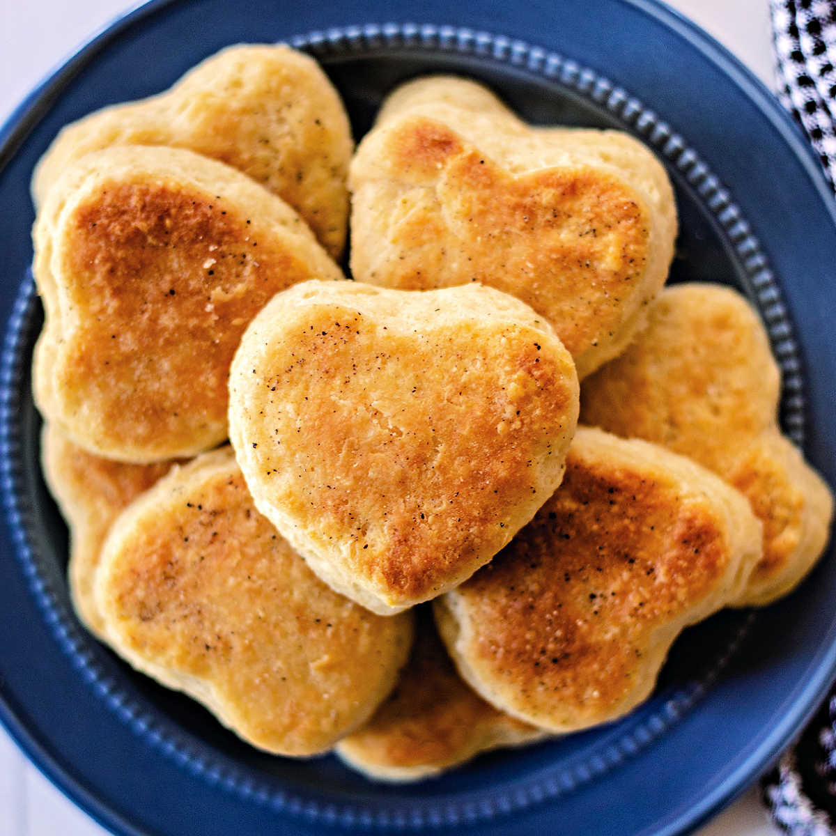 heart shaped bread flour biscuits stacked on a blue plate.