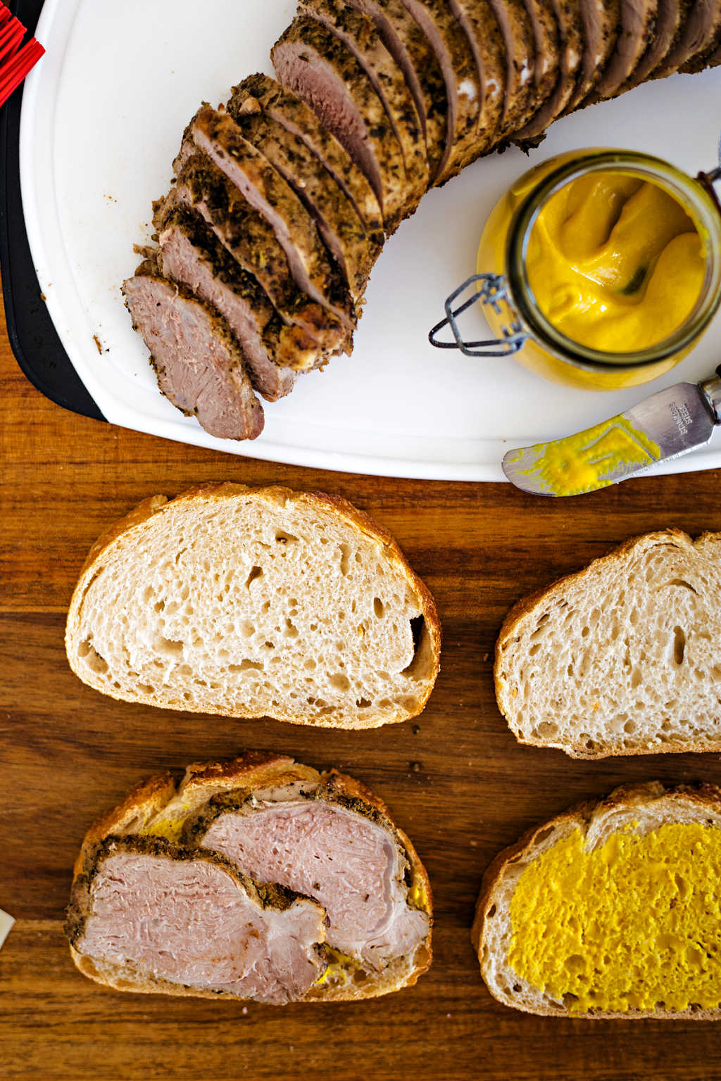 sliced pork tenderloin and bread on a table ready to assemble sandwich cubano.