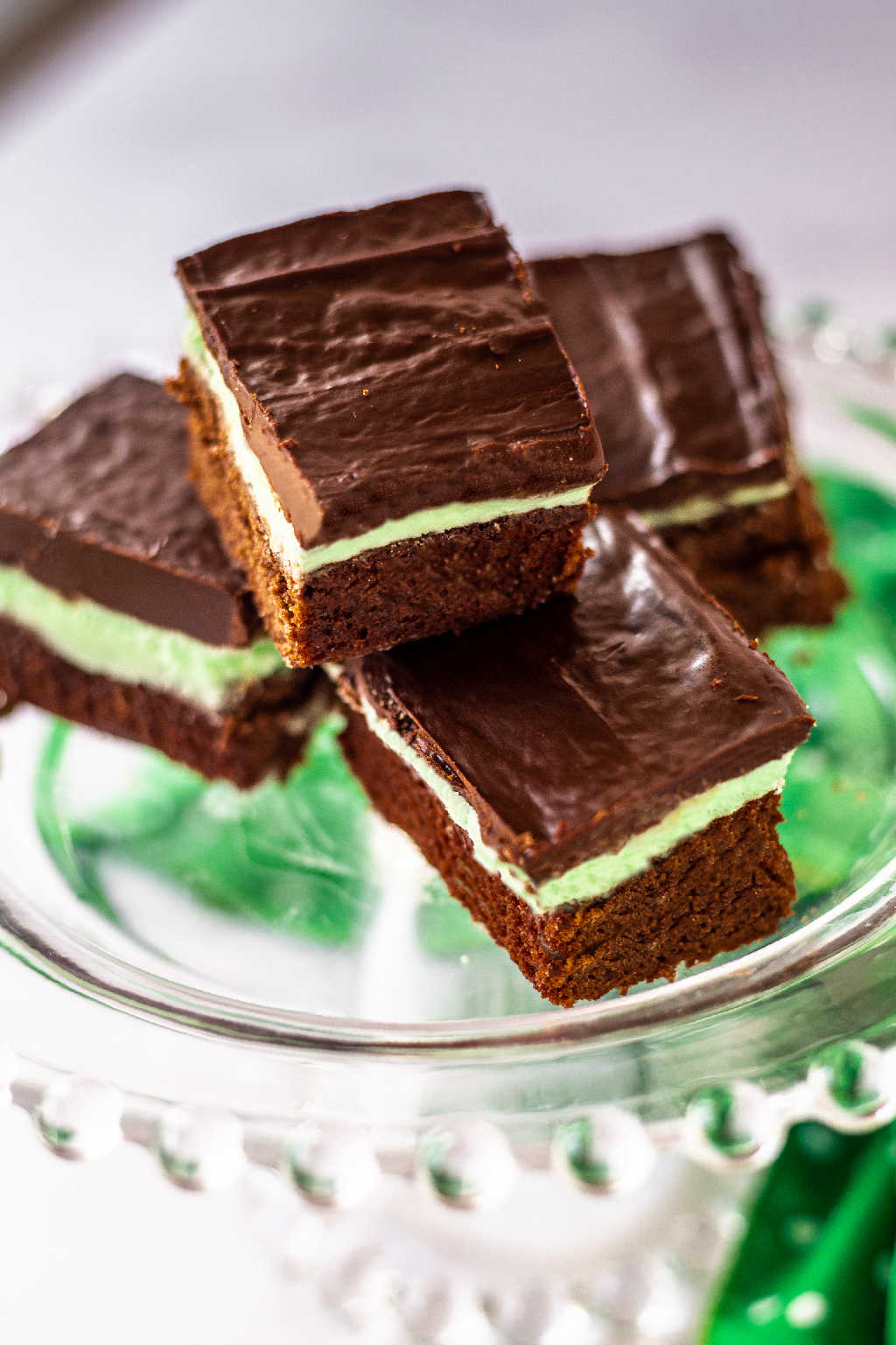 fudge mint brownies on a pedestal plate with a sprig of mint.