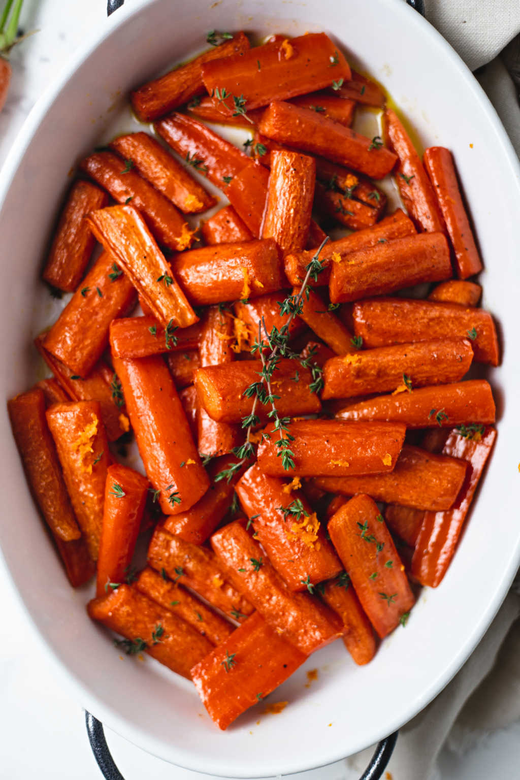 roasted carrots with honey in a white dish on a table.
