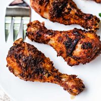 air fryer chicken legs on a white platter on a table.