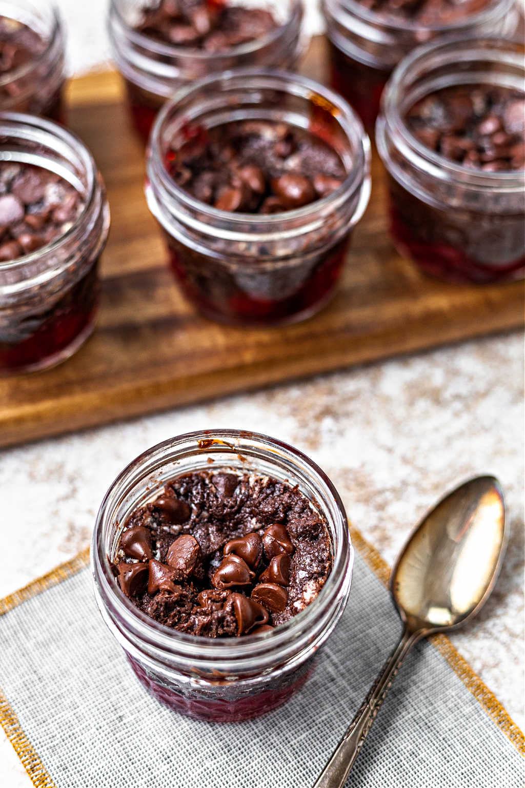Cherry chocolate dump cake in a small mason jar with an antique spoon on a table.
