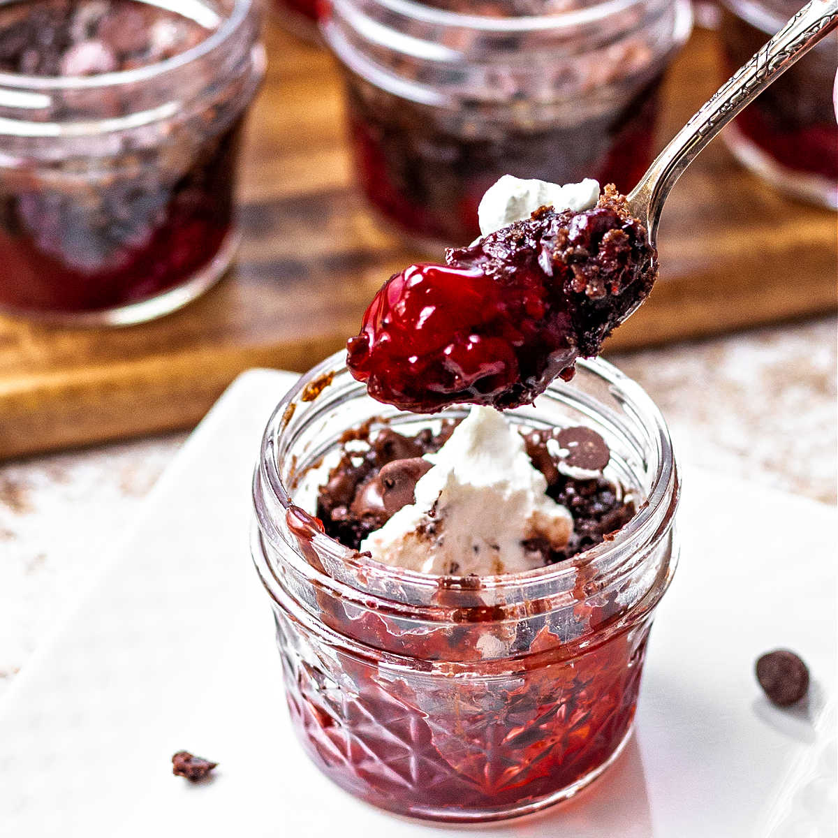 a spoon of chocolate cherry dump cake in a jar on a table.