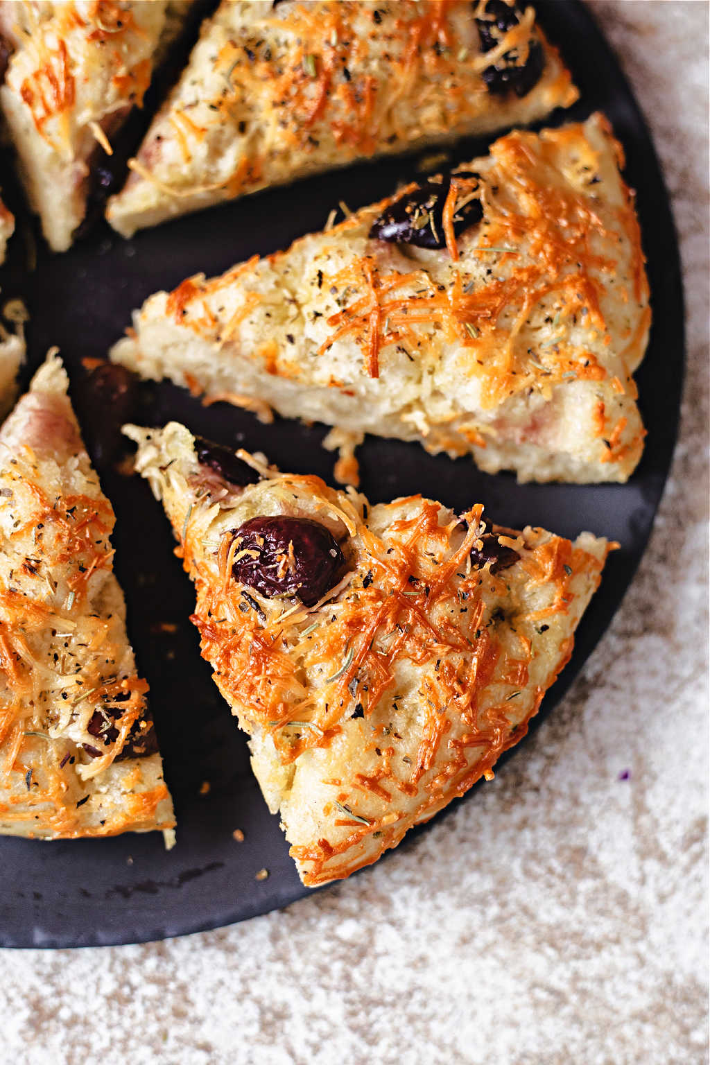 wedges of greek olive focaccia on a black stone platter.