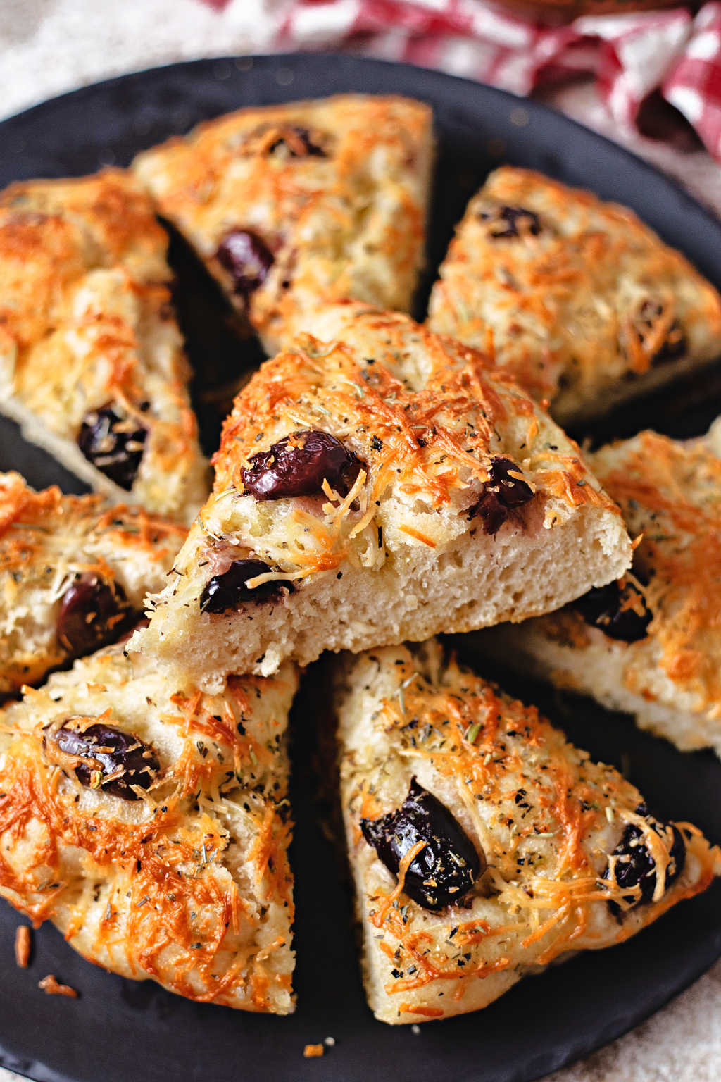 wedges of greek olive focaccia on a black stone platter.