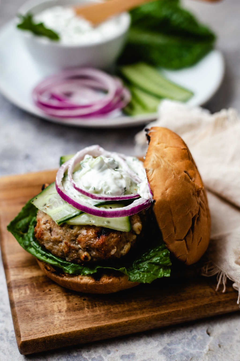 a greek turkey burger on a wooden board on a table.