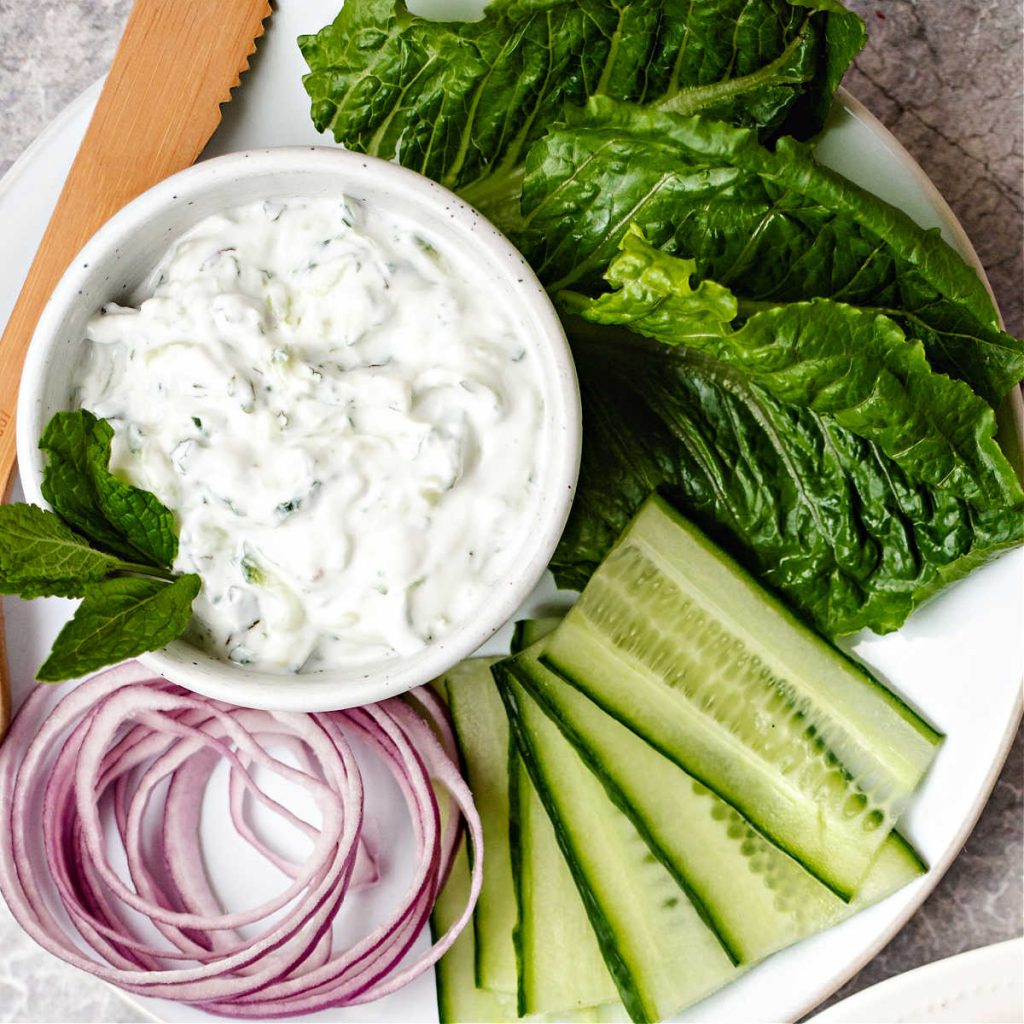 condiments for greek turkey burgers on a white plate.