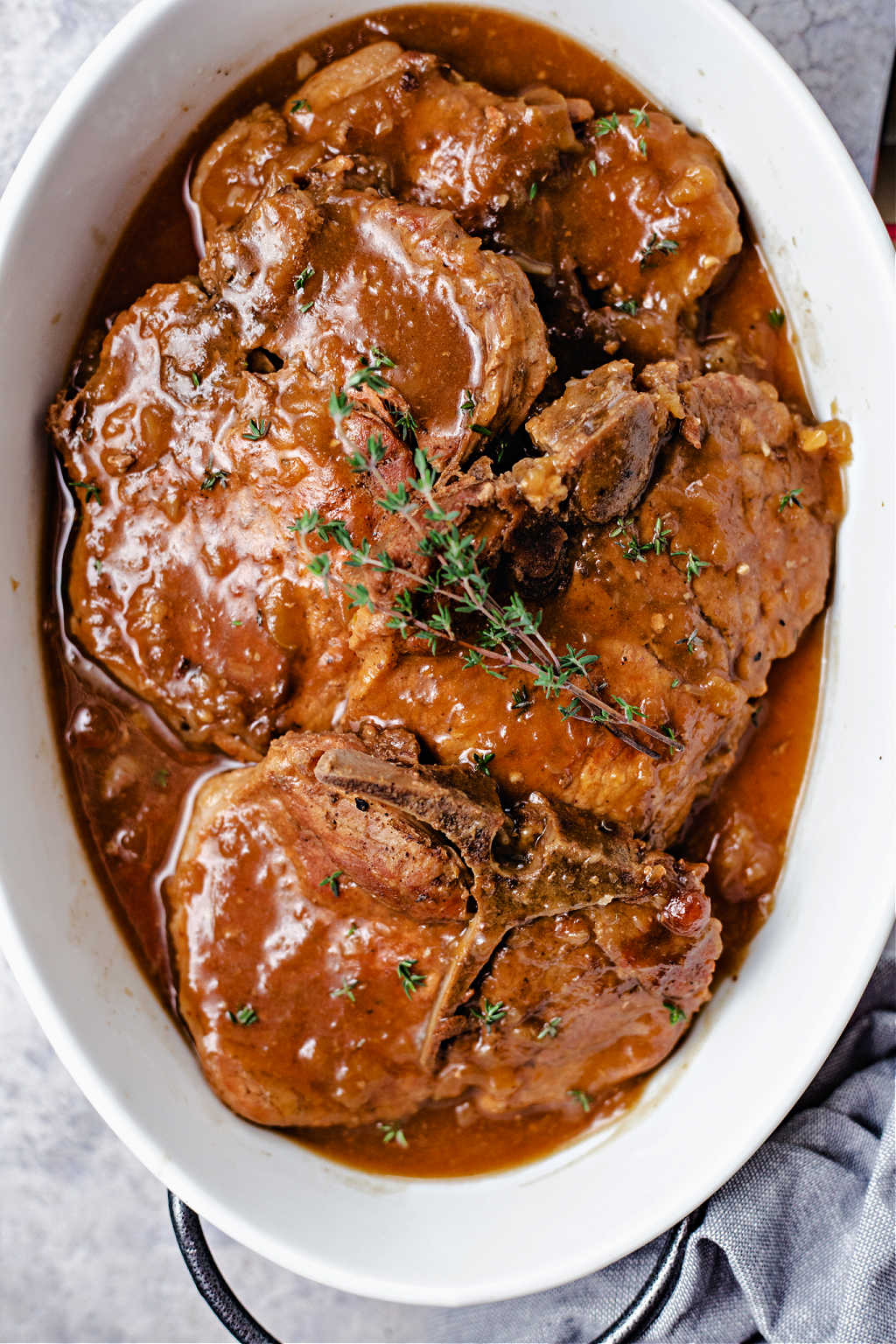 instant pot pork chops with apple gravy in an oval white serving dish.