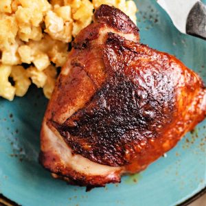 smoked chicken thigh on a blue plate with mac and cheese.